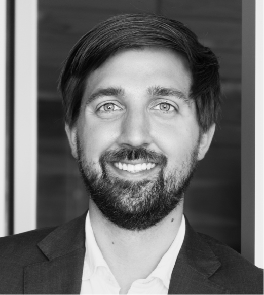 A man with beard and suit jacket smiling.