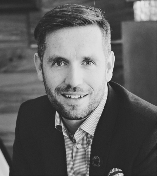 A man in a suit and tie smiling for the camera.