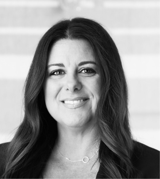 A black and white photo of a woman in front of stairs.