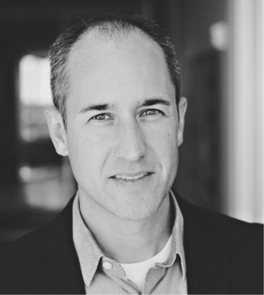 A man in a suit and tie smiling for the camera.