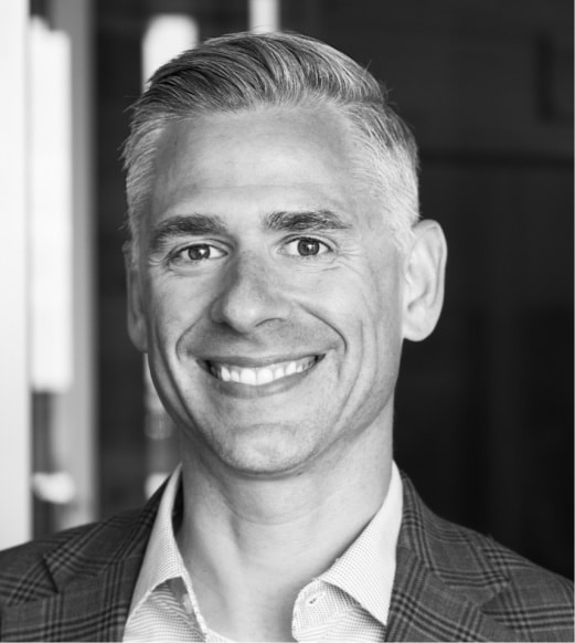A man with grey hair and a suit smiling.