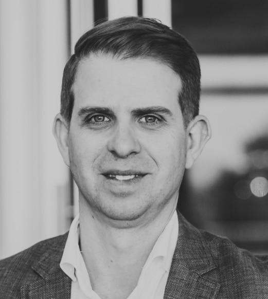 A man in a suit and tie smiling for the camera.