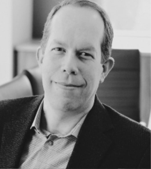 A man in suit and tie sitting down.